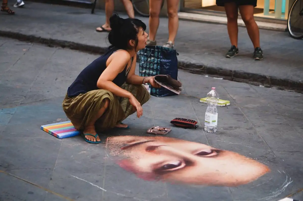 woman sitting on concrete pavement near Mona Lisa painting