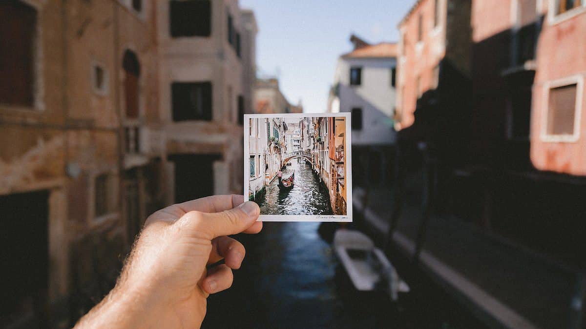 person visiting Italy and holding photo of grand canal