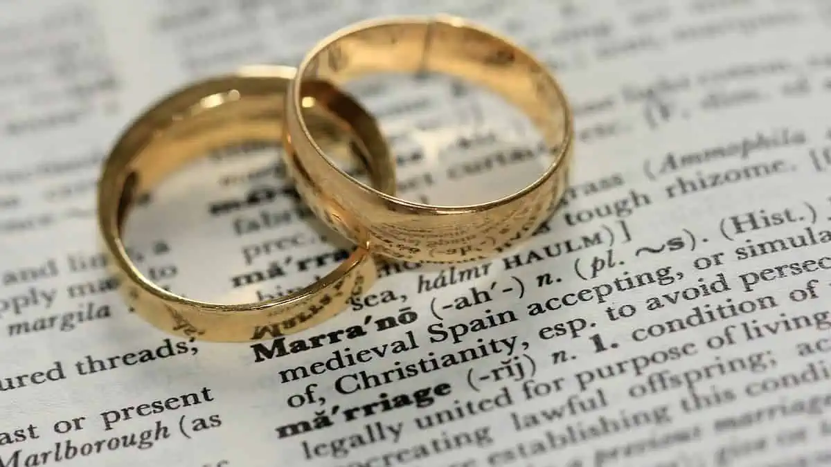 two gold-colored wedding rings on a book