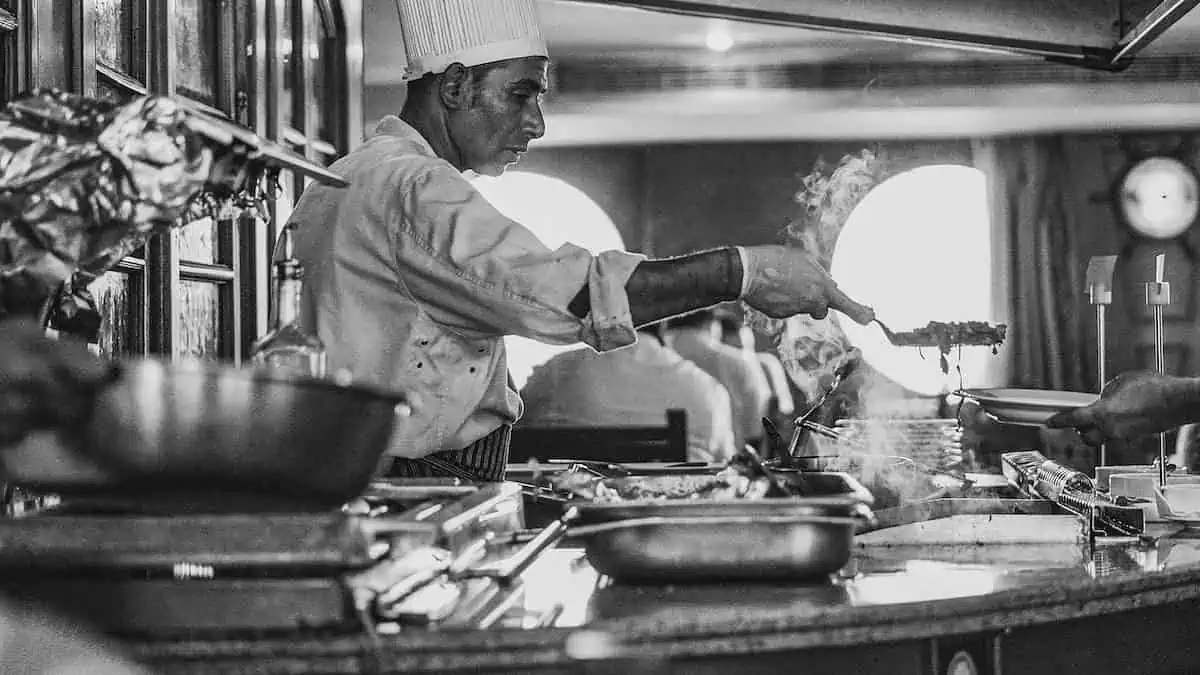 photo en niveaux de gris d'un homme en train de cuisiner